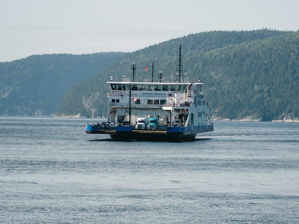 Ferry carrying trucks between wooded hills